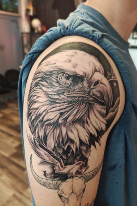 Tattoo of a bald eagle perched atop a bull skull